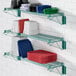 A green Regency wall-mounted wire shelf with dishes and plates on it.