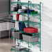 A Regency green wire wall shelf with metal brackets holding plastic containers.