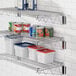 A chrome Regency wall-mount wire shelf with food containers and cans on it.