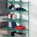 A green metal Regency wall-mount wire shelf with blue trays on it.