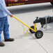 A man using a yellow Snap-Loc trailer and equipment mover with black handle wheels a trailer.