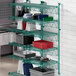 A green wire shelving unit with dishes and pots on it.