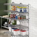 A Regency chrome wire shelving unit with food items on a shelf.
