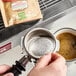 A person using a Caffe Borbone coffee machine to make coffee with a coffee filter.