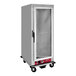 An Avantco stainless steel holding cabinet with a clear glass door on wheels.