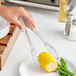 Clear polycarbonate scallop grip tongs serving corn on the cob at a salad bar.