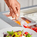 A person using Choice clear polycarbonate tongs to serve themselves salad from a salad bar.