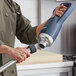 A man in a chef's uniform using a Galaxy medium-duty immersion blender in a professional kitchen.