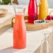 A table with a Visions clear plastic carafe and glasses on it.