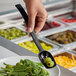 A person using a black Choice perforated salad bar spoon to serve green salad.