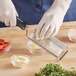 A person using a Microplane dual grater to grate garlic over a bowl.