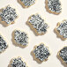 A group of cookies with white frosting and black sparkling sugar on top.