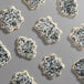 A collection of sugar cookies decorated with white icing and coarse black sanding sugar.