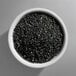 A white bowl filled with coarse black sanding sugar.