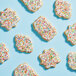 A cookie with white frosting and colorful Adourne rainbow sparkling sugar sprinkles.