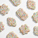 An assortment of sugar cookies decorated with white icing and colorful coarse rainbow sanding sugar.