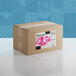 A cardboard box with a label that reads "Adourne Coarse Pink Sanding Sugar" and has pink squares on it.