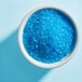 A bowl of Adourne Light Blue sparkling sugar crystals.