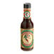 A close up of a Pickapeppa Original Sauce bottle with a label showing a green and red bird.