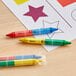 A group of double-sided hexagonal restaurant crayons in yellow and green wrappers on a table.