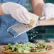 A person grating cheese with a Microplane stainless steel grater.