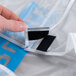 A hand attaching a black velcro strap to white fabric on a Carlisle dish caddy cover.