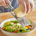 A person using a Microplane fine grater to grate cheese onto a salad.