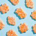 A group of cookies with white frosting and Adourne Orange sparkling sugar.