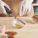 A person in gloves using a Microplane grater to grate spices into a bowl.