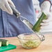 A hand in a glove uses a Microplane Black Ribbon Grater to cut a cucumber.
