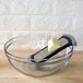 A Microplane fine grater grating butter into a glass bowl.