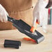 A person using a Microplane mandoline to cut a carrot.