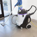 A woman using a ProTeam wet / dry vacuum to clean a room.