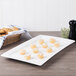 A white rectangular porcelain platter with food on a table.