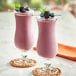 Two glasses of Makai Organic sweetened acai smoothies with pink berries on top.