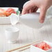 A person pouring sake into a white porcelain sake bottle.