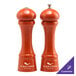 Two orange Chef Specialties pepper mills with silver tops on a counter.