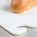 A loaf of bread on a white San Jamar Cutting Board with a hook.