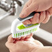 A person using a 3M Scotch-Brite hand and nail brush to wash their hands.