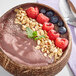 A bowl of smoothie with berries and oats topped with nuts and berries.