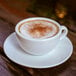 A cup of coffee with Violife vanilla coffee creamer on a saucer.