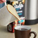 A person pouring Violife vanilla coffee creamer into a cup of coffee.