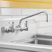 A backsplash-mount faucet with a 12-inch swing nozzle, full-flow aerator, and lever handles.