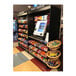 An ASM stainless steel micro market stand with double shelves holding snacks and candy.