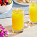 A group of glasses of Ruby Kist orange juice next to a bowl of fruit.