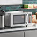 A Solwave stainless steel commercial microwave on a counter with a coffee maker.