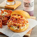 A burger with Capital City Mambo Sauce on a wooden board.