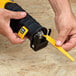 A person using a DeWalt yellow reciprocating saw to cut wood.