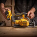 A person using a DeWalt cordless circular saw with a yellow and black design.