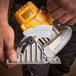 A person using a DeWalt cordless circular saw with a yellow handle.